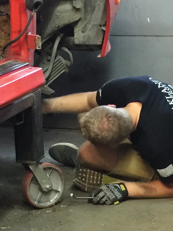 29617607001_a80371b50e_c Person lying on the floor reaching under a vehicle with a tool in hand