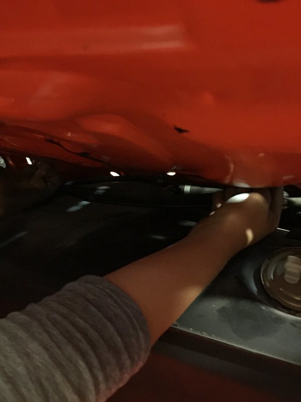 29663098606_874b141b93_c A person reaching under a red vehicle, possibly performing maintenance or repairs