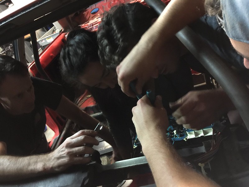 29663160316_76ec30a0d9_c Several people collaborating to fix or assemble machinery inside a vehicle frame