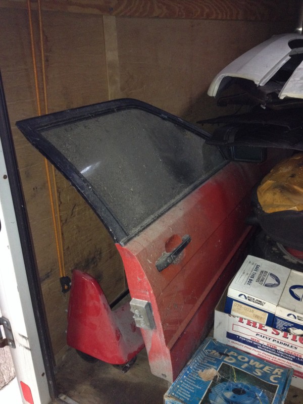 29675817595_11b5f2a1b6_c Red car door resting vertically inside a storage space with stacked boxes nearby