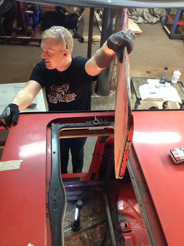 29709872560_1c0c6a76c7_c Person lifting a hatch door on a red vehicle, revealing the interior floor and a small light inside.