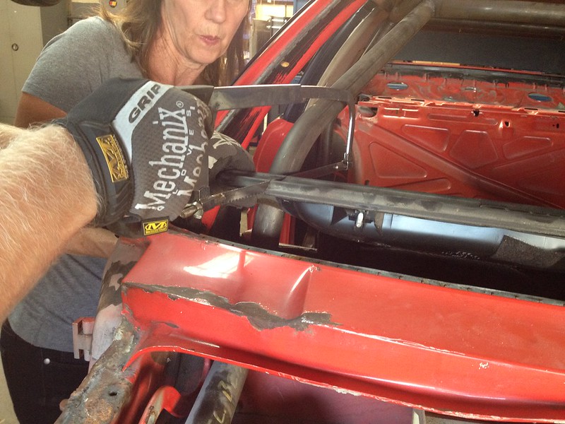 29846193135_685dba667c_c A person wearing a Mechanix glove using a handsaw to cut a metal part on a red vehicle frame while another person observes