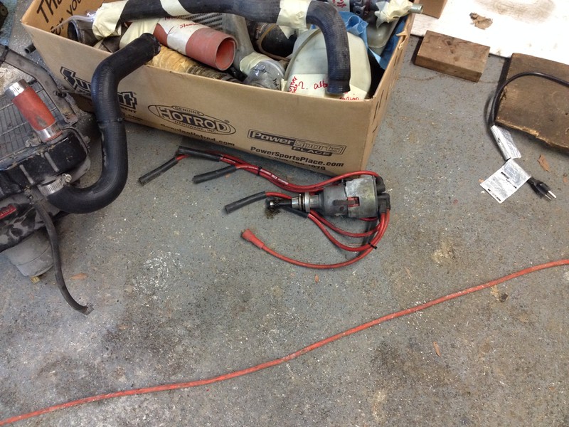 30370830921_4874eb21fa_c Box containing various automotive hoses and parts on a garage floor with a distributor and red ignition wires nearby