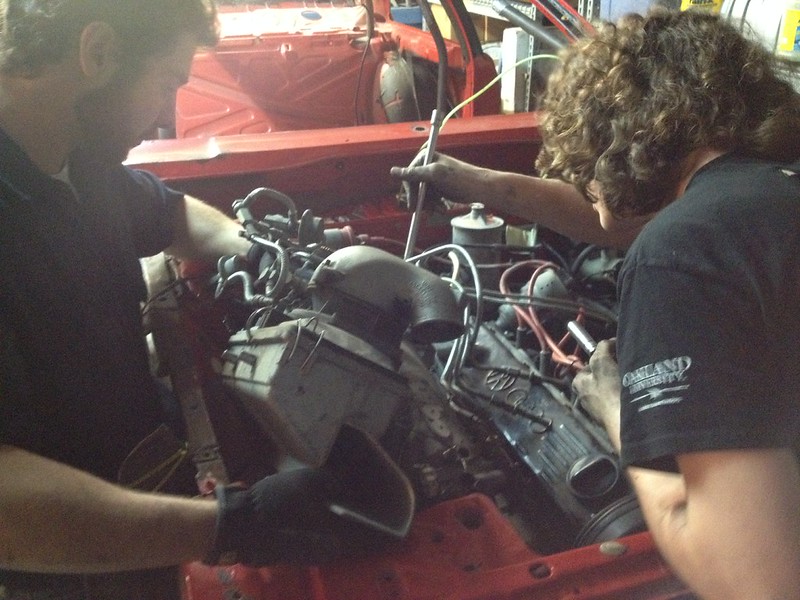30457636945_8f9c787e38_c Two people working together on a car engine in a garage
