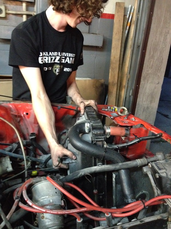 30457667855_ee4ffd3042_c Person working on a car engine, handling the radiator inside the engine bay
