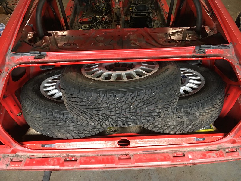 30662941222_441bb974ca_c Three winter tires stacked inside the open trunk of a red car