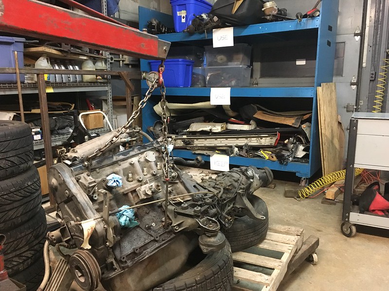 31457655743_0002d06e63_c UR Quattro Engine block suspended by a chain hoist in a cluttered auto repair workshop with shelves and tires