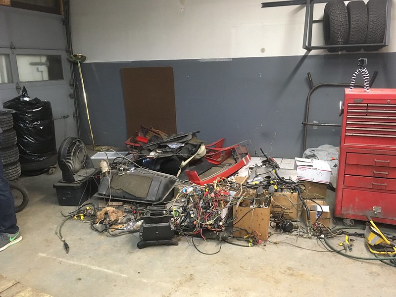 31659146935_b76f1a6d2c_c Messy workshop floor with tangled wires, car parts, stacks of tires, and a red tool chest