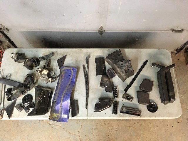 A tabletop displaying various automotive parts and accessories, including handles, panels, and connectors in shades of black and blue.