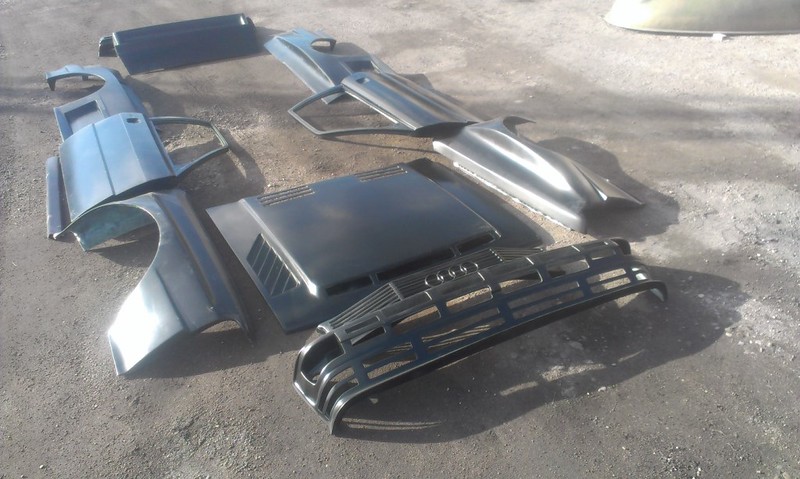 32427920150_17623911a0_c Disassembled black car body parts including bumpers, a hood, and side panels laid on the ground