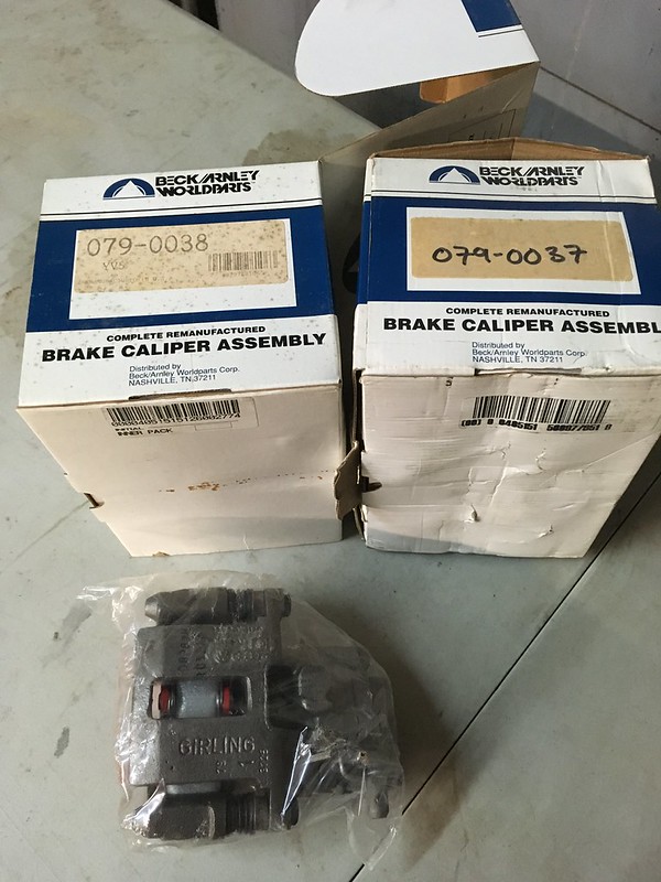Two boxes of remanufactured brake caliper assemblies labeled with part numbers, alongside a packaged brake caliper.