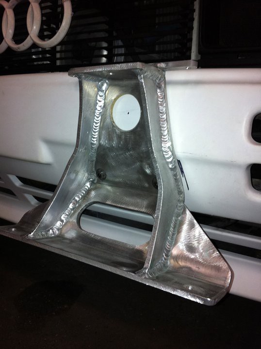 Close-up of a metallic, custom-designed automotive part with a polished aluminum finish, mounted on the front of a vehicle.