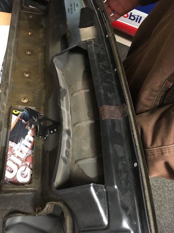 32868602416_dfc3177c00_c Person holding a black metal bracket over a car interior panel with weatherstripping and bolt holes