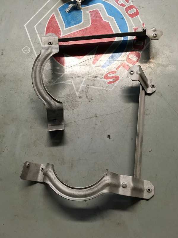 Metal components on a gray surface, featuring a curved and straight bracing structure.