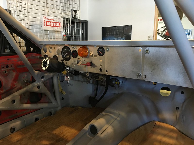 Interior view of a UR Quattro rally  dashboard with gauges, switches, and a steering column, showcasing a stripped-down design.