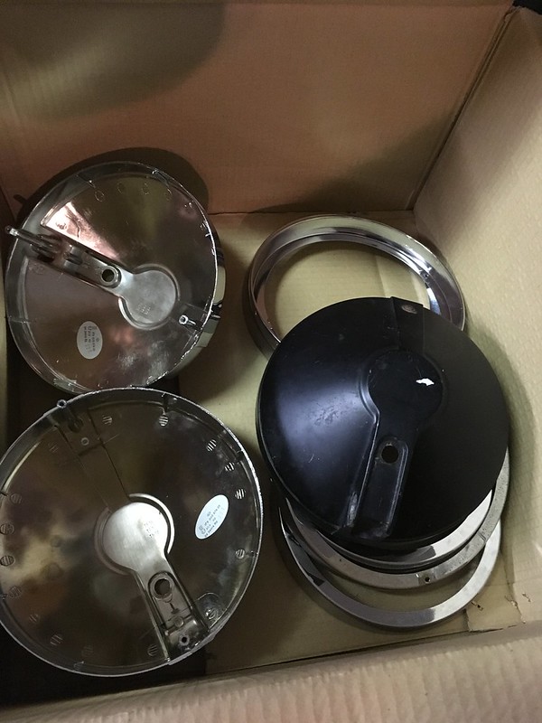 Four metal Hella 3000l parts in a cardboard box