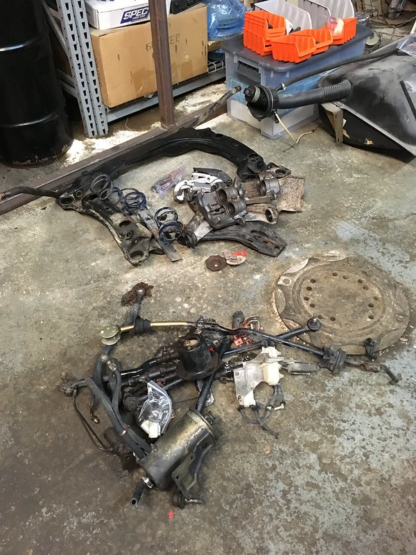 Various UR Quattro parts and springs scattered on a workshop floor near shelves and storage containers