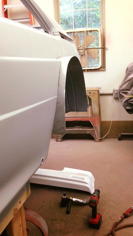 Close-up view of a UR Quattro's rear fender and bodywork in a workshop, with tools and a fan visible in the background.