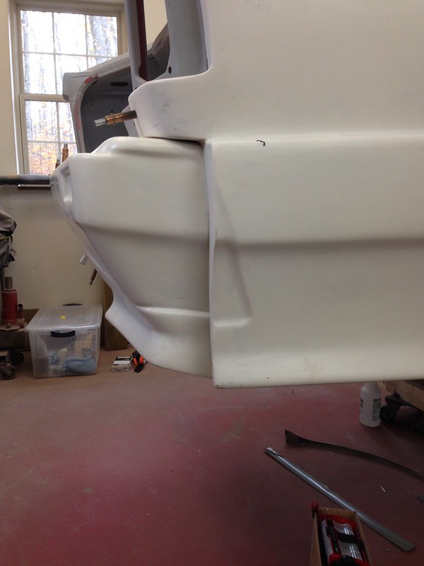 Close-up view of a white UR Quattro bumper in a workshop, showing its contours and textures.