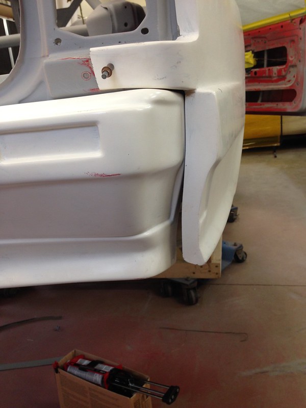 Close-up view of a white UR Quattro body part with a detailed edge, showing painted and unpainted areas in a workshop setting.