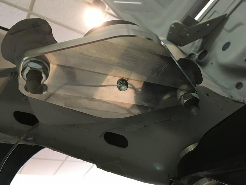 Close-up view of a shiny metal UR Quattro component with bolts, likely a suspension mount, mounted under a vehicle.