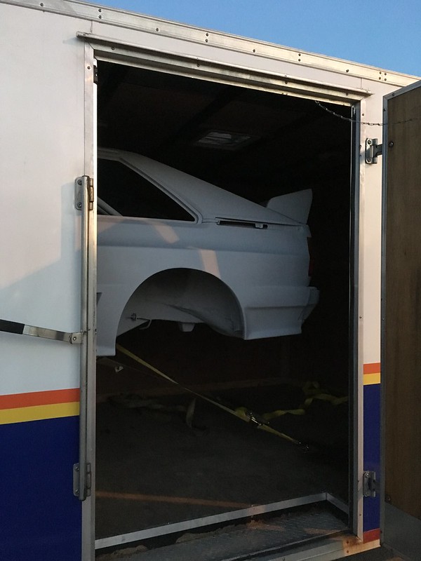 A white UR Quattro is partially visible inside a trailer, secured with straps, with the rear showing through the open door.