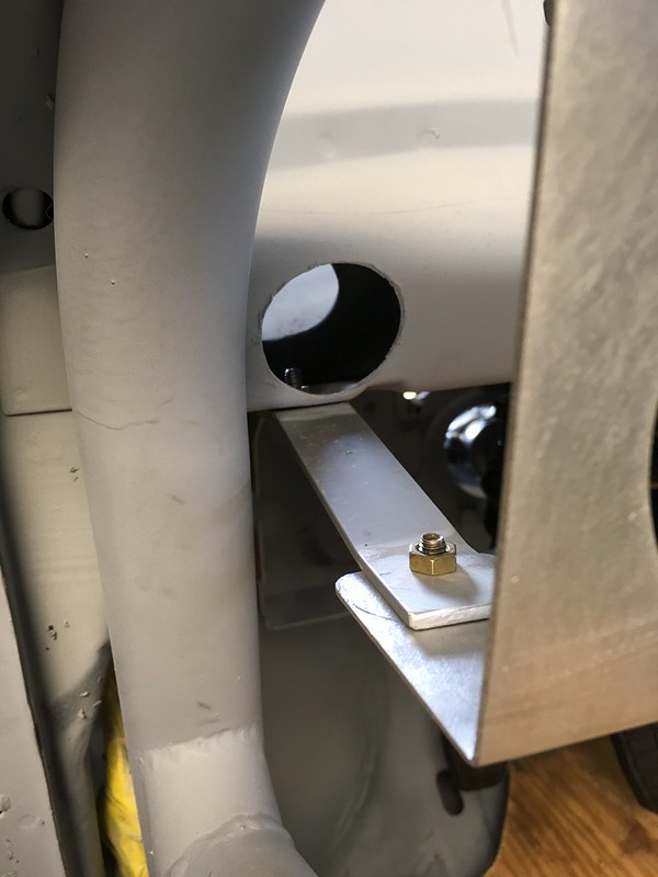 Close-up view of metal components including a rounded hole, a metallic plate, and a nut on a mechanical assembly.