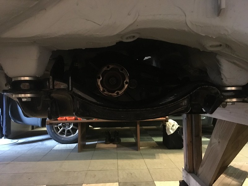 View of a UR Quattro 's undercarriage showing suspension components and other mechanical parts in a garage setting.