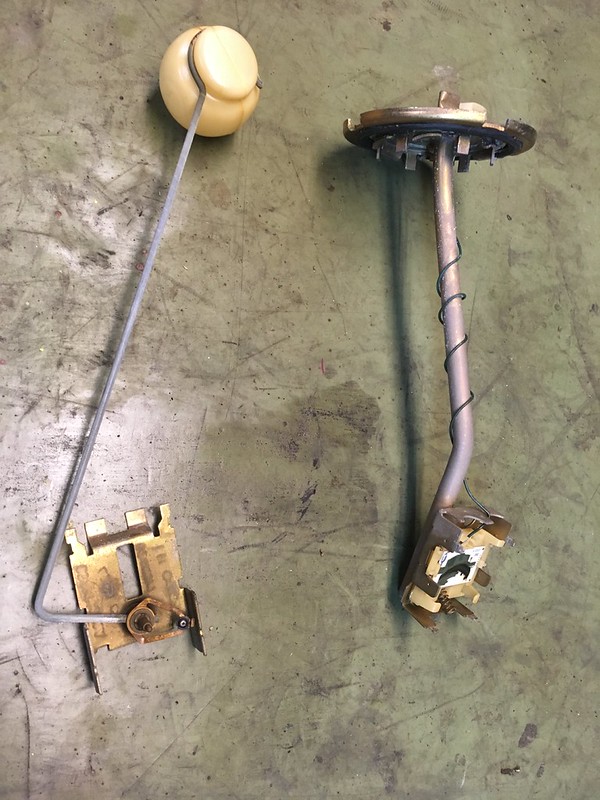 A UR Quattro fuel sender unit consisting of a float, a metal rod, and an electrical connector, laid on a green surface.