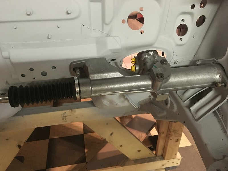 Close-up view of a UR Quattro 's steering rack mounted on a chassis, showcasing the rack and pinion mechanism with rubber boot and metal fittings.