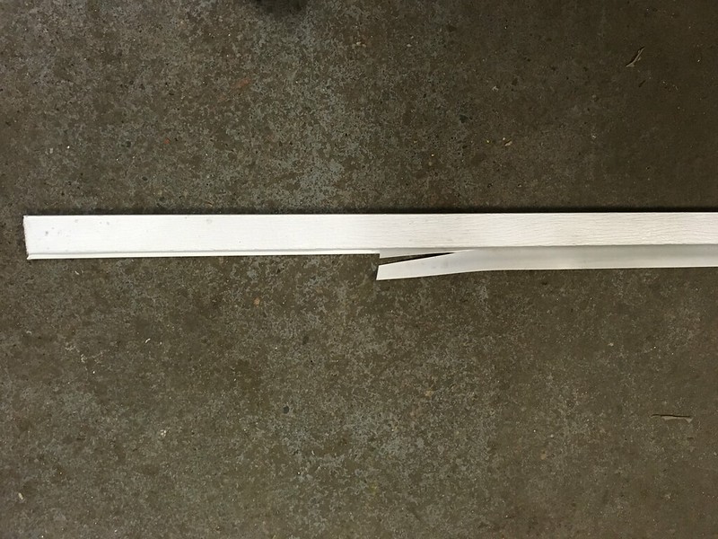 A broken white wooden plank lying on a concrete surface.