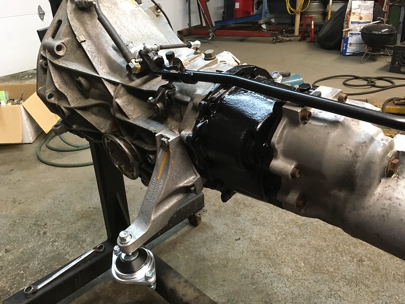 Close-up view of a UR Quattro transmission with a black engine mount attached, set on a workbench in a garage.