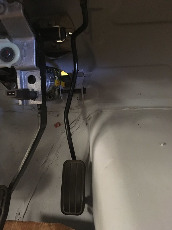 Close-up view of a UR Quattro rally car's interior showing a throttle pedal, linkage, and surrounding components in a white-painted compartment.